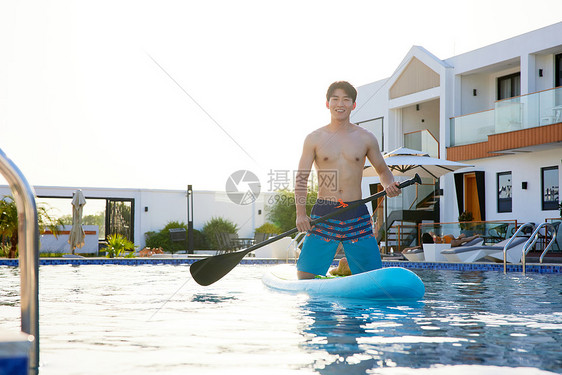 酒店泳池里高兴地划船的帅哥图片