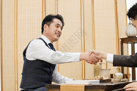商务人士在茶馆握手合作背景图片