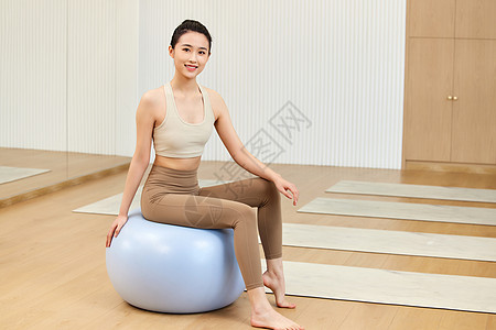 运动美女坐在瑜伽球上高清图片