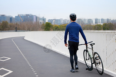 推着自行车行走的男性背影图片