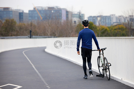 推着自行车行走的男性背影图片