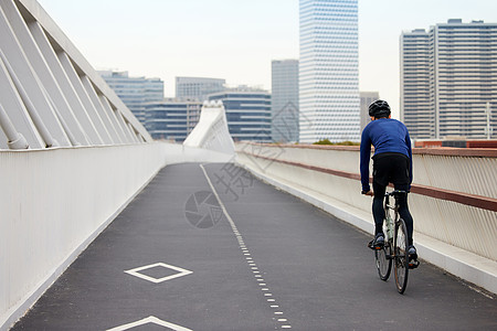 靠道路右侧骑行的男性背影图片