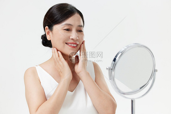 看镜子涂抹乳液的中年女性图片
