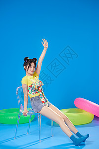 蓝色背景夏日美女坐在椅子上图片