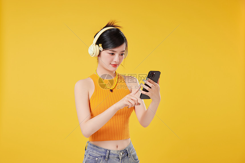 戴着耳机的少女操作手机图片