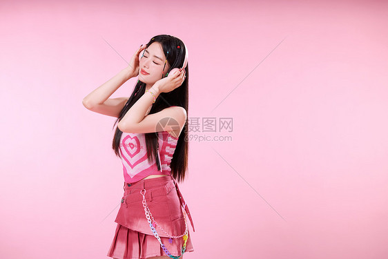 时髦女生头戴粉色耳机听音乐图片