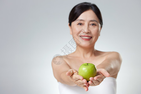 中年女性手中的青苹果图片