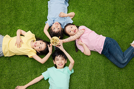 儿童躺在草地上触摸冠军奖杯图片