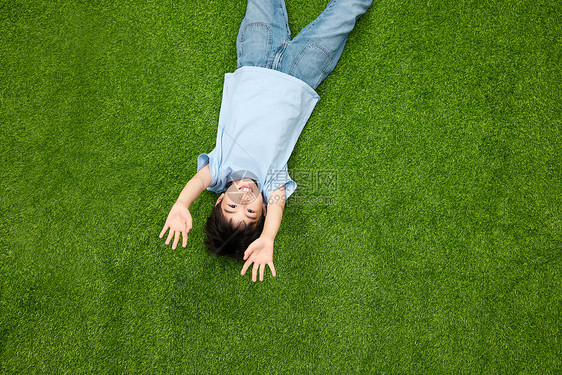 躺在草坪上开心打招呼的小男孩图片