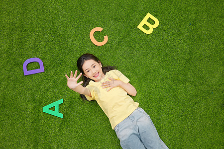 小女孩躺在有字母的草地上图片