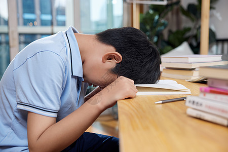 小学招生学习时埋头睡觉的男孩背景