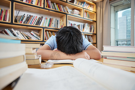 疲劳学习的男孩趴在书桌上补觉高清图片