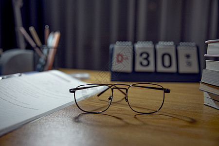 高考倒计时日历书桌上倒计时日历前的眼镜特写背景