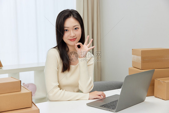电脑前做出OK手势的女性形象图片