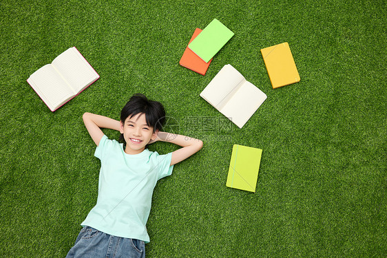 小女孩躺在铺满书本的草地上图片