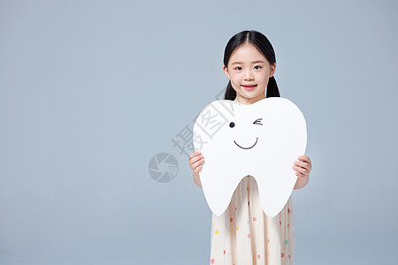 小学生卡通小女孩手举牙齿模型背景