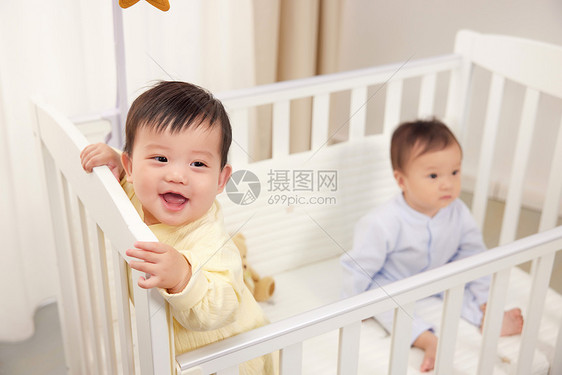 婴儿床上开心玩耍的双胞胎图片