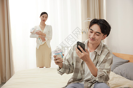 抱孩子的母亲和拿着奶瓶玩手机的父亲背景