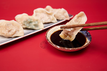 春节习俗红色背景筷子夹起水饺蘸醋特写背景