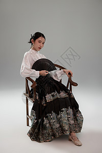 手拿扇子坐在椅子上的新中式马面裙美女图片