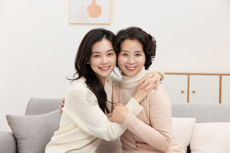 在一起幸福母女在沙发上拥抱在一起背景