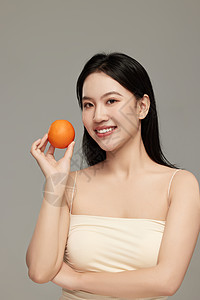 微笑向镜头展示手中橙子的气质女人高清图片