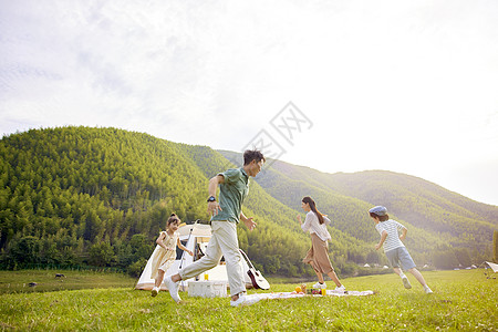 孩子快乐玩耍一家人在草地上奔跑背景