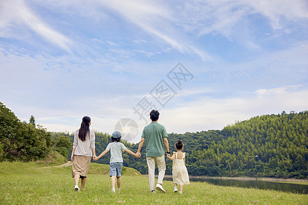 一家玩耍一家四口站在草地上快乐的散步背景