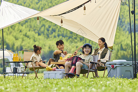 促销帐篷一家四口坐在草坪上游玩背景