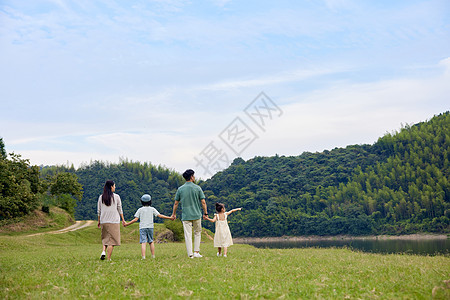 幸福的一家人在草原上手拉手散步图片