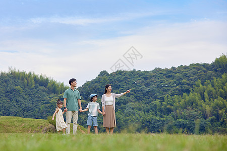 一家四口在草地上散步背景图片