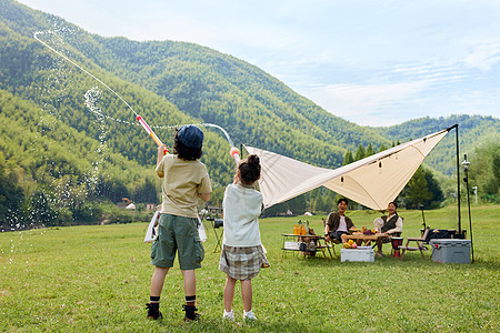 假期郊游户外露营两个孩子在玩水枪背景