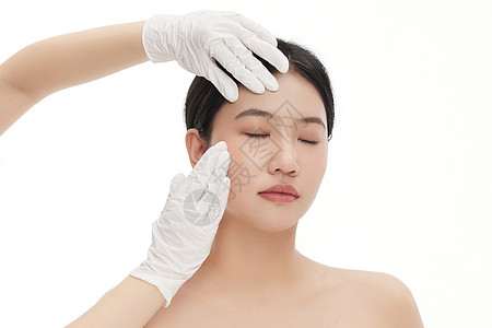 美容素材美白整形医生用双手触摸确定女人脸部状态背景