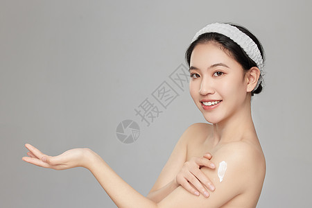 微笑展示手臂上身体乳的年轻女孩高清图片