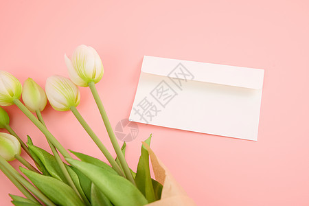 粉色桌面上的白色信封和郁金香图片