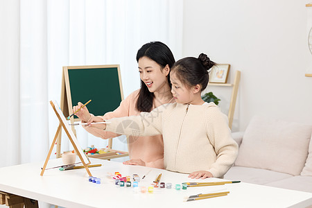 年轻妈妈正和女儿一起画水彩画图片