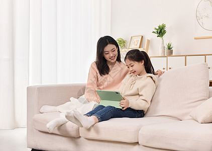 儿童沙池沙发上陪伴女儿看平板的年轻妈妈背景