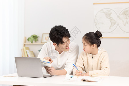 正严肃指导女儿作业的年轻男子图片