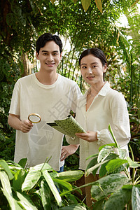 一对情侣在植物园拿着放大镜观察植物背景