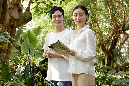 女性一对情侣在植物园拿着放大镜观察植物背景