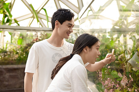 情侣在植物园拿着放大镜观察植物图片