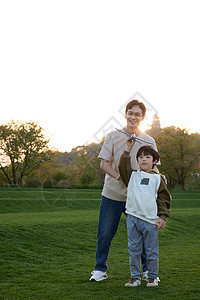 酷玩爸爸带着儿子在草坪上玩飞机玩具背景