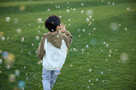 小男孩在草坪上吹泡泡图片