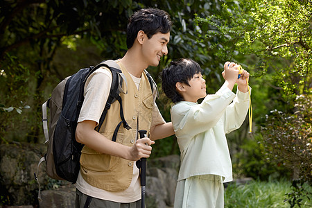 年轻帅气男装小男孩用相机拍山景背景