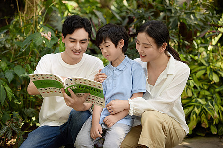 一家人在植物园坐着看植物科普书图片