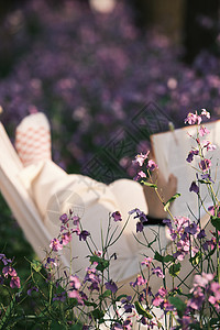 花丛中躺在吊椅上阅读的女孩高清图片
