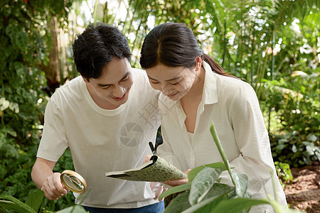 植物园里拿着放大镜和笔记本的专业人员图片