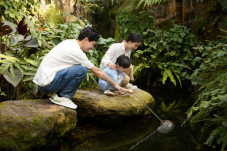 植物园里拿网兜抓鱼的一家三口图片