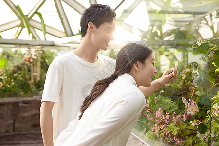 植物园里观察植物的年轻小情侣图片