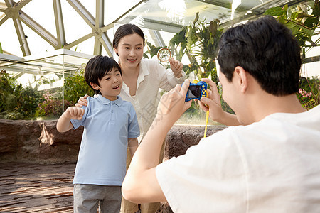 植物园里父亲正在给母子俩拍照图片
